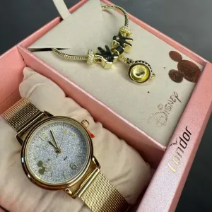 RELOGIO CONDOR FEMININO LINHA DISNEY DOURADO PULSEIRA ESTEIRA COM FUNDO MIKEY E GLITER ACOMPANHA ACESSORIOS PULSEIRA COM BERLOQUES PERSONALIZADO PERSONAGEM CO2035NKZ/K4K - COR AÇO DOURADO