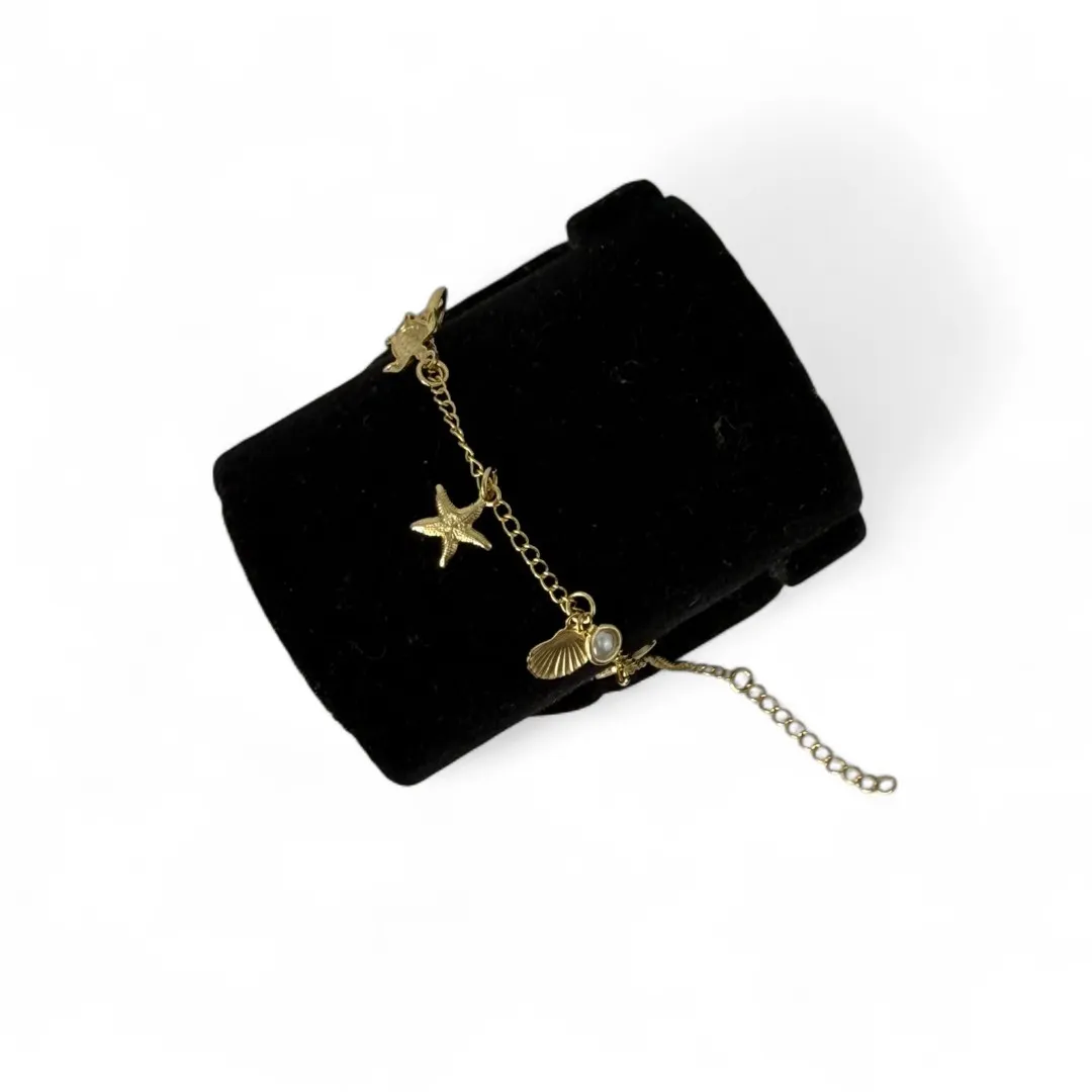 TORNOZELEIRA ELO GRUMET COM PENDURICALHO ESTRELA DO MAR, CONCHA, RABO DE BALEIA, TARTARUGA E PÉROLA COM EXTENSOR - BANHADO A OURO 18K