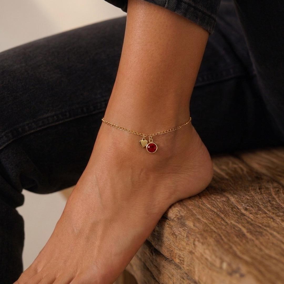 TORNOZELEIRA ELO GRUMET FINO COM CORAÇÃO LISO PEQUENO E PONTO DE LUZ VERMELHO- BANHADO A OURO 18K